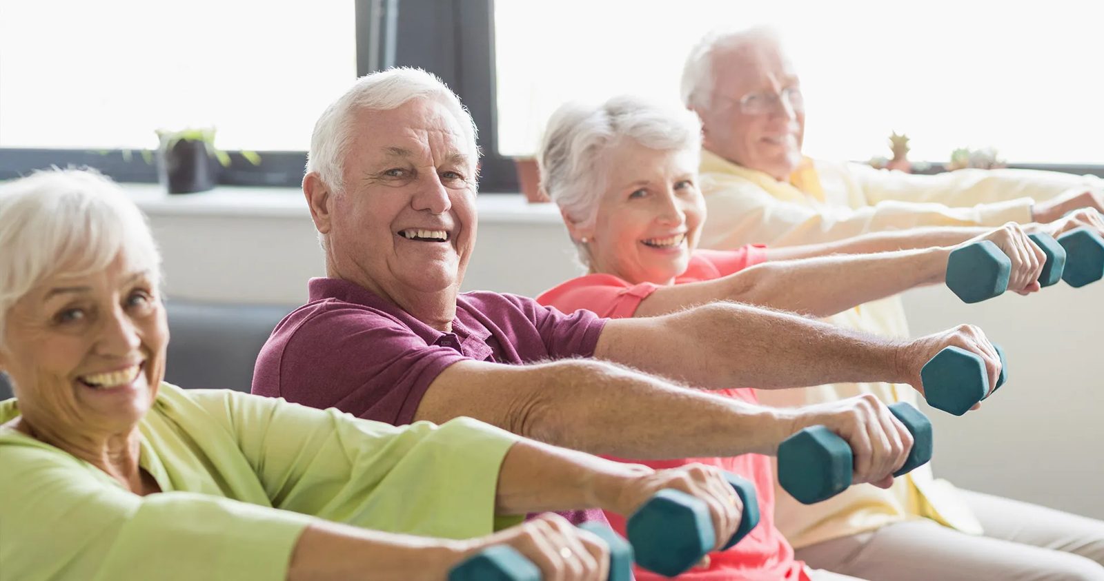 Older adults smiling while exercising with dumbbells in a group class